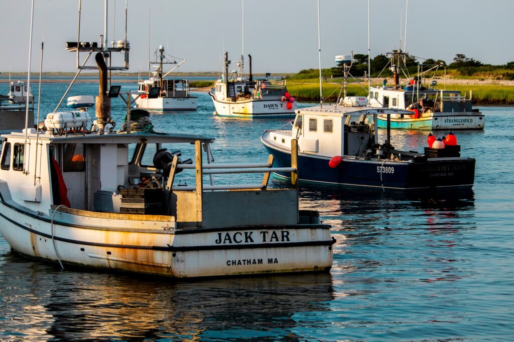 The Chatham fishing fleet is moored in the harbor as the sun begins to set for the day. Where to stay in Cape Cod includes many places like Chatham.