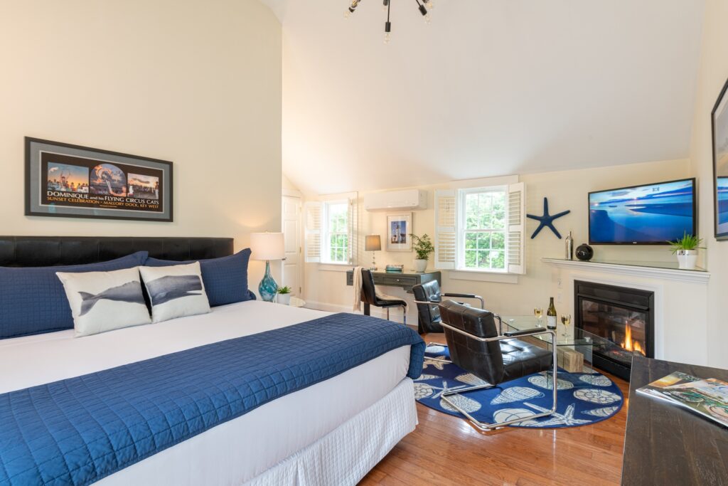 A guest room with a king bed and a seating area by a fireplace at a bed and breakfast in Cape Cod.