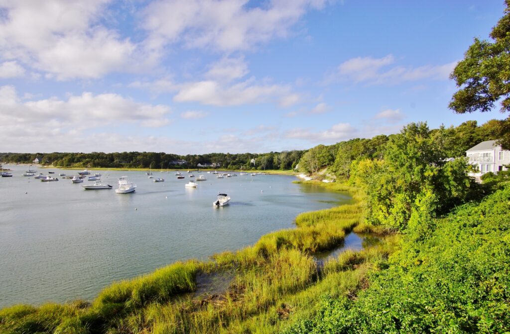 Green land by the water filled with boats, a perfect view for a Cape Cod couples getaway.